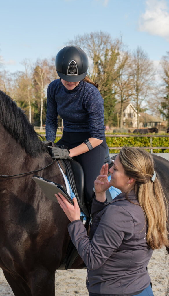 Ruiterfysiotherapeut Sophie Delemarre neemt een hartslagmeting af bij een ruiter.